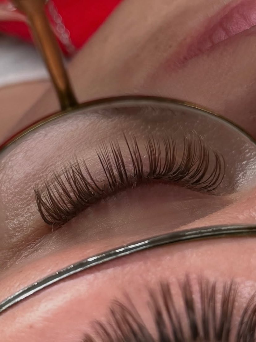 A finished set of brown lash extensions shown in a mirror